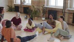 High angle shot of group of young multiethnic dancers resting on floor in studio, smiling and chatting - Powered by Shutterstock - Get 15% off with code: PIKWIZARD15