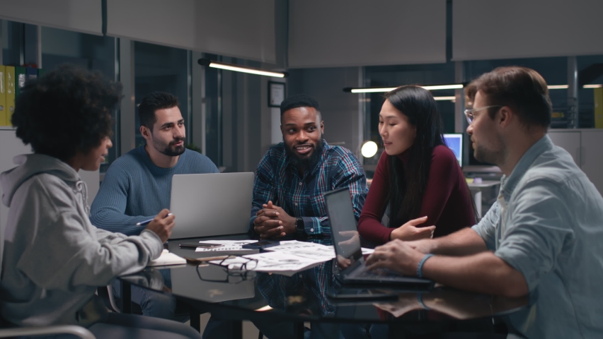 Group of diverse businesspeople meeting around table In office. Multiethnic young colleagues brainstorm and discuss late in office | Shutterstock HD Video #1086230438