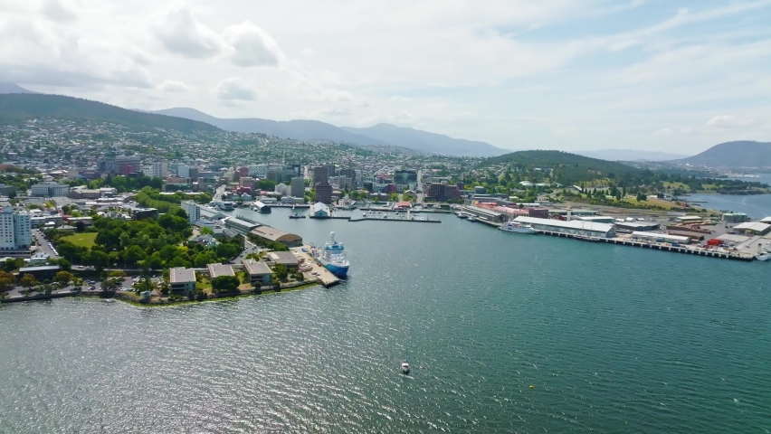 High angle aerial drone footage of Sullivans Cove, the harbour area of Hobart, capital of the island state of Tasmania, Australia. Mount Wellington in the background is covered in clouds.