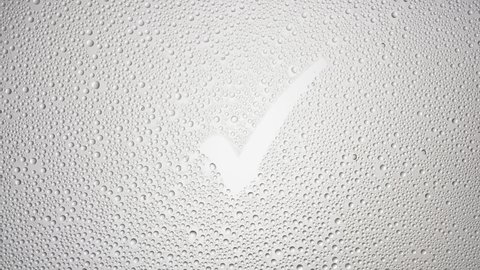 Checkmark printed on the wet glass blown off with air stream on grey background | antiperspirant advertisement
