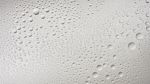 Water drops blown off the wet glass surface on grey background | Overlay foreground or background for skin care moisturizing products