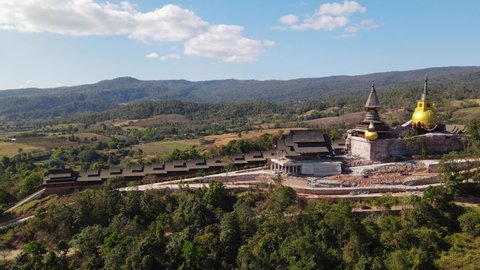 Aerial descending footage of Wat Somdet in Phu Ruea while a car is moving towards the right with a gorgeous landscape, Ming Mueang, Loei in Thailand.
