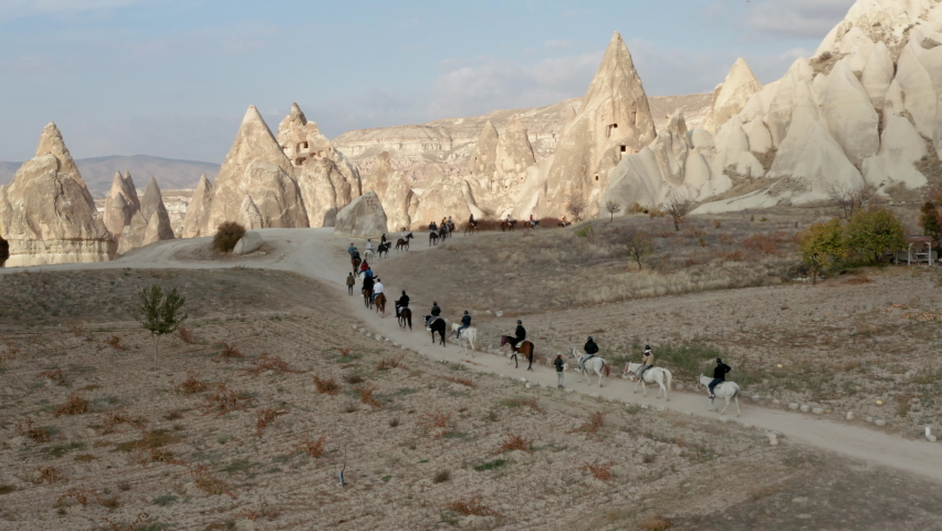 Turkish Men And Caravan Of Horses Passing Across The Cappadocia Landscapes, Turkey. - Wide Shot
