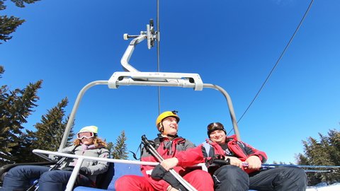 Bansko, Bulgaria - circa Jan, 2022: Selfie of three skiers on ride on cableway ski lift transporting people to mountain summit slopes