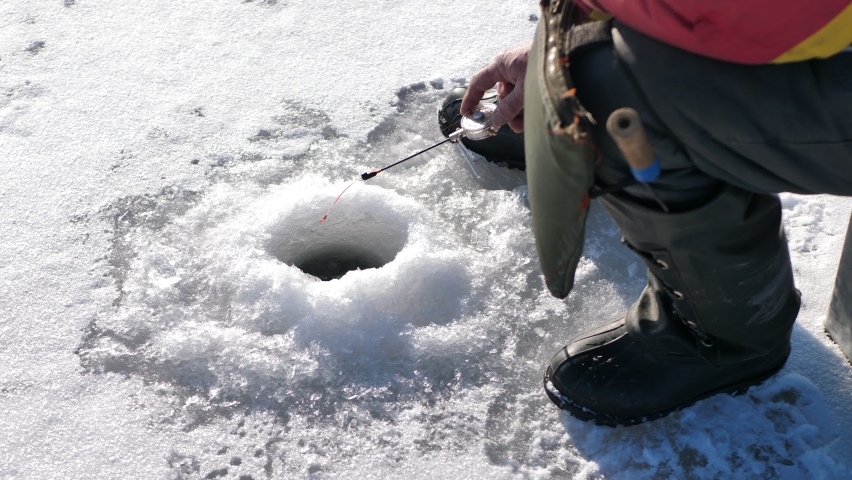 Ice fishing on a frozen lake. A man is fishing in an ice hole