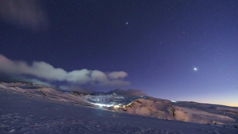 Timelapse of the night sky over ski area of snowy mountain landscape with radio telescope, Sierra Nevada, Spain