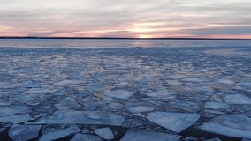 Broken thick ice pieces floating on calm water surface near river bank at bright purple sunset on cloudy sky in winter aerial view - Powered by Shutterstock - Get 15% off with code: PIKWIZARD15