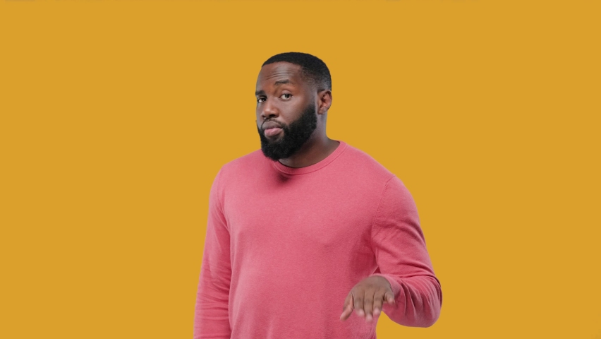 Curious interested delightful funny amazed African American man holding hand near ear and trying to hear the information on yellow | Shutterstock HD Video #1086257216