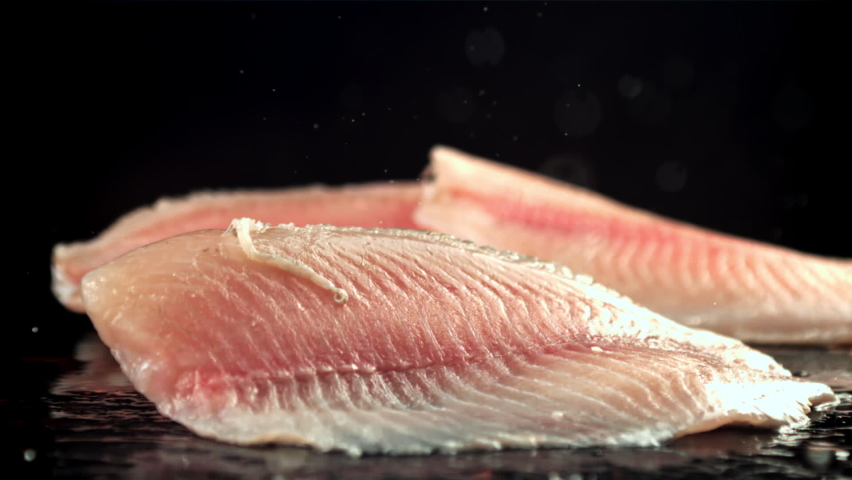 Fish fillets fall on a wet table with splashes. On a black background. Filmed on a high-speed camera at 1000 fps. High quality FullHD footage | Shutterstock HD Video #1086258068