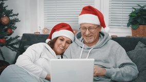 A happy middle-aged couple with santa hats congratulate their relatives and friends via video link on a laptop with Christmas sitting at home on the couch. - Powered by Shutterstock - Get 15% off with code: PIKWIZARD15