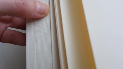 finger leafing through blank sheets of a thick book notepad