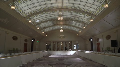 PETERSBURG, RUSSIA - DECEMBER, 17, 2021: Holiday dinner in restaurant. Decorated hall for reception, celebration party, wedding, anniversary or birthday. White tables with food. Glass ceiling.