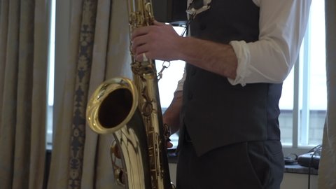 Saxophonist playing saxophone at the party. Man with golden sax player. Wind musical instrument at the party or concert indoors. 