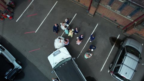 Enfield , United Kingdom (UK) - 01 23 2022: Rising aerial view above newlywed couple, Limousine and wedding ceremony guests at charming village church