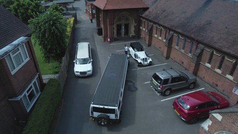 Enfield , United Kingdom (UK) - 01 23 2022: Expensive wedding limousine vehicles parked outside charming English church aerial descending view