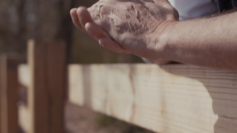Man Against Farm Fence Clasps Hands In Slow Motion