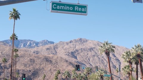 Palm trees and sky, Palm Springs street, city near Los Angeles, semaphore traffic lights on crossroad. California desert valleys summer road trip on car, travel USA. Mountain. Camino Real road sign