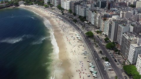 Aerial view Rio de Janeiro Copacabana Brazil. Sandy crowded beach with umbrellas and ocean waves in the city with skyscrapers and beautiful architecture.