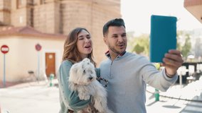 Young couple holding dog having video call at street
