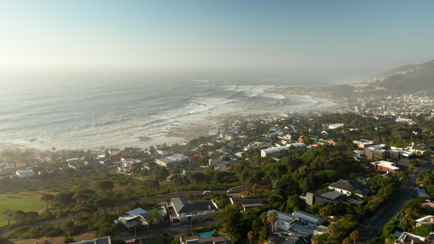 Fly Over Misty Seascape Of Camps Bay Beach With Foamy Rolling Waves In Cape Town, South Africa. Aerial Drone