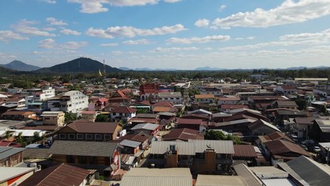 Aerial footage towards the left revealing rooftops and mountains and sky in the horizon, Walking Street, Chiang Khan, Loei in Thailand.