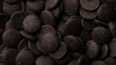 Dark chocolate chips top view rotation. Camera moves away from the object. 4K UHD video