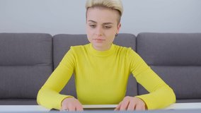 Beautiful tomboy woman working on laptop. 4k stock video of white female doing distant work on modern notebook pc connected to internet. Freelancer person studying online during lockdown
