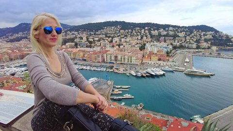 Smiling sitting on top rooftop view of panorama of the Nice city and Port Lympia in Blue Coast of France. Aerial view of cityscape with lighthouse from the panoramic terrace of Colline du Chateau park