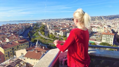 Woman looking Nice: French city skyline in Provence of France. Aerial view of Nice cityscape from panoramic bell tower Tour Saint-Francois with Promenade du Paillon park and beach in Blue Coast.