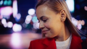 Close Up Portrait of Beautiful Caucasian Woman Smiling, Looking at Camera, Standing in Night City with Bokeh Neon Street Lights. Happy Confident Young Female with Blond Hair and Blue Eyes.
