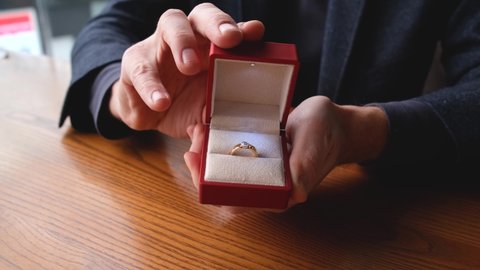 a man's hands open a box with a wedding ring