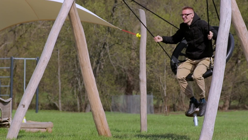 Man swings on a hanging nest swing in the green park like in childhood