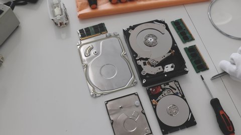 Opened hard disk drive. Technician repairing hard drive in service center workshop, hands close up.