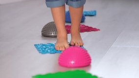 Little boy walking over spiked half balance massage balls. Flat feet correction exercise. close up Shot video. Slow motion