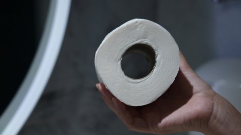 Closeup view 4k stock video footage of female hand holding roll of white soft toilet paper 