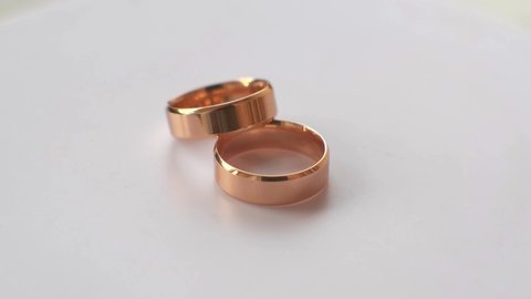 Two gold wedding rings rotate on a white background. macro photography.