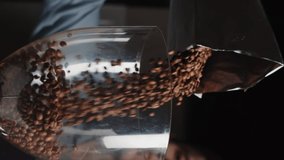 Close up of barista pours coffee beans into a coffee grinder from package in slow motion. Vertical video template for smartphone web promo.
