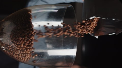 Close up of barista pours coffee beans into a coffee grinder from package in slow motion. Vertical video template for smartphone web promo.