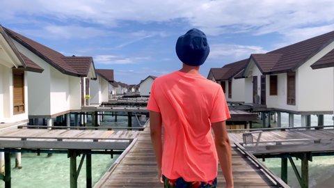 a man walks along the pier near the water bungalows in the Maldives. Travel time. Romantic honeymoon. Enjoys the rest and his beloved
