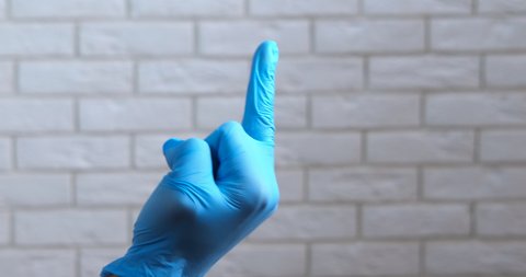 Angry woman show fuck. Angry medical worker in blue latex glove show the middle finger in the hospital.