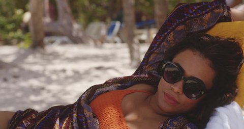 Latin Brunette Lady Relaxing on Sun Lounger in the Shade Enjoying Beach holiday, Medium Shot