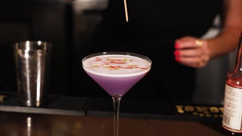 Colorful purple cocktail with artistic garnish by mixologist bartender slow motion 4k 30p
