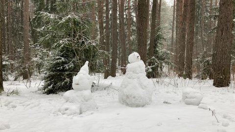 Snowmen in strong blizzard among pine trees. 