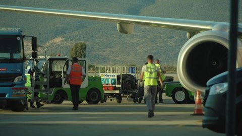 Bodrum, Turkey - October 10, 2021: Airport staff uploading of luggage from landed aircraft and aviation ground handling in airport Bodrum.