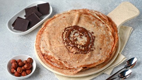 Pancakes with chocolate and nuts. Pouring chocolate on pancakes. Pouring chocolate on crepes. Maslenitsa blini. Shrovetide holiday. Shrove tuesday. Pancake day