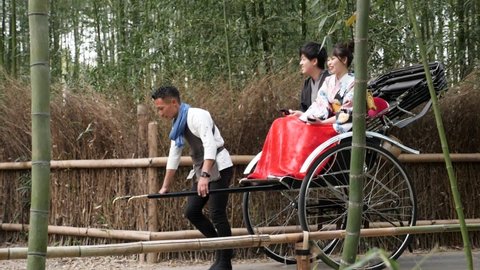 Kyoto, Japan - Febuary, 1, 22: Tourists enjoying a rickshaw ride during summer at arashiyama bamboo forest in Kyoto, japan. High quality footage