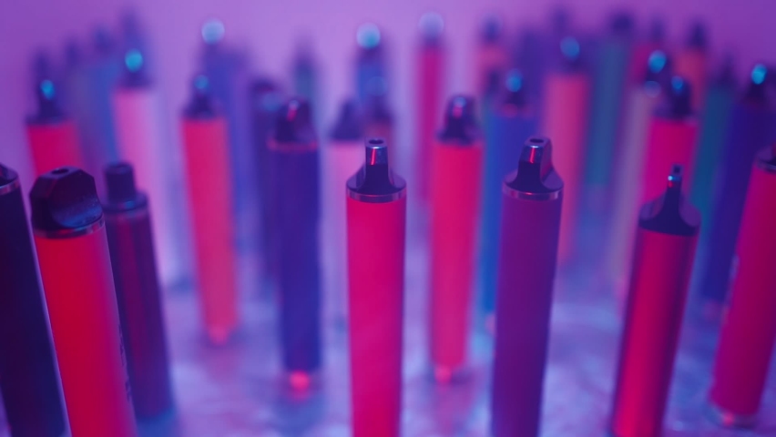 Lots of e-cigarettes and vapes in neon lighting and illuminated ambulance flashers. Concept of bad habits. Slow motion.  | Shutterstock HD Video #1086312275