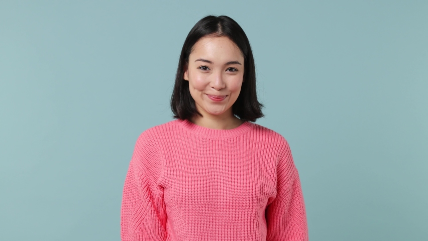 Smiling happy young woman of Asian ethnicity 20s years old wears pink shirt pointing fingers down on workspace area copy space mock up isolated on plain pastel light blue background studio portrait Royalty-Free Stock Footage #1086313925