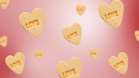 Flying and wiggle of different diameters heart-shaped yellow candies with label "Love" on trending red color gradient background. Romantic Love concept for mother's, St. Valentine's and women's day.