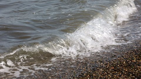 Waves Wash Over A Pebble Beach With Small Stones And Rocks. Sea Surf On A Summer Day On The Beach. The Waves Of The Sea In Focus. ProRes
